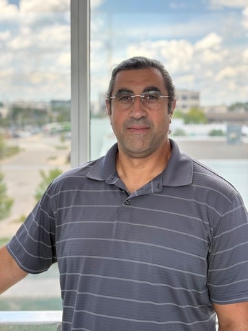 a man with glasses smiling in front of a window