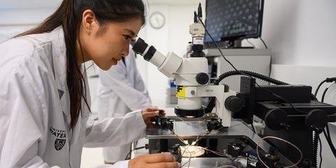 a woman looking through a microscope