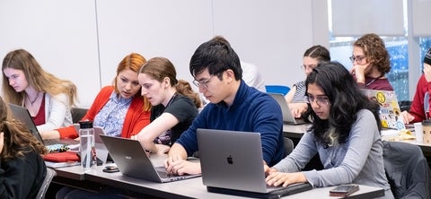 Students sitting at a desk looking at their computers