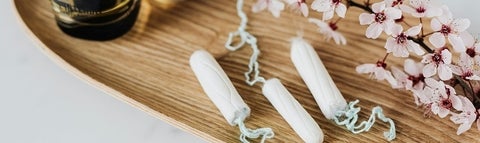 wooden board with white and pink flowers and three white tampons