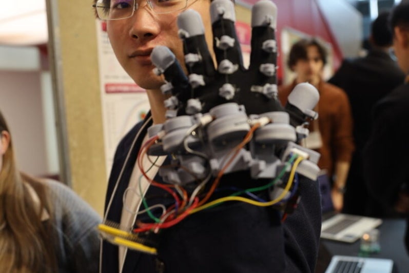 a man with glasses wearing a glove with wires