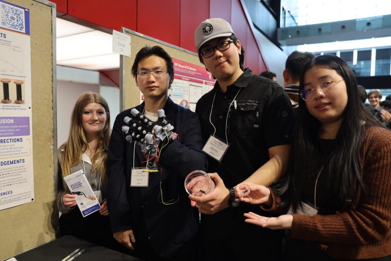two women and two men holding up a glove 