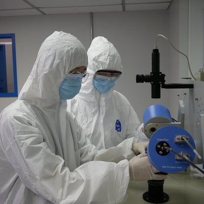 Technicians in cleanroom suits working on equipment