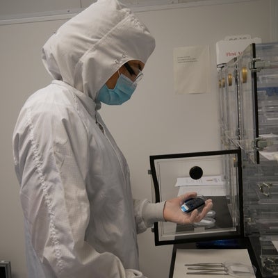 Technician in clearoom suit looking at a wafer