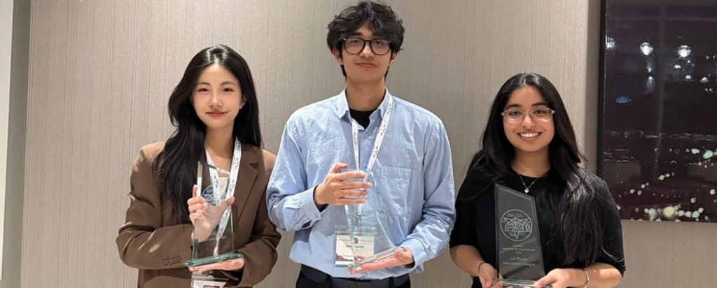 two women and a man holding glass trophies