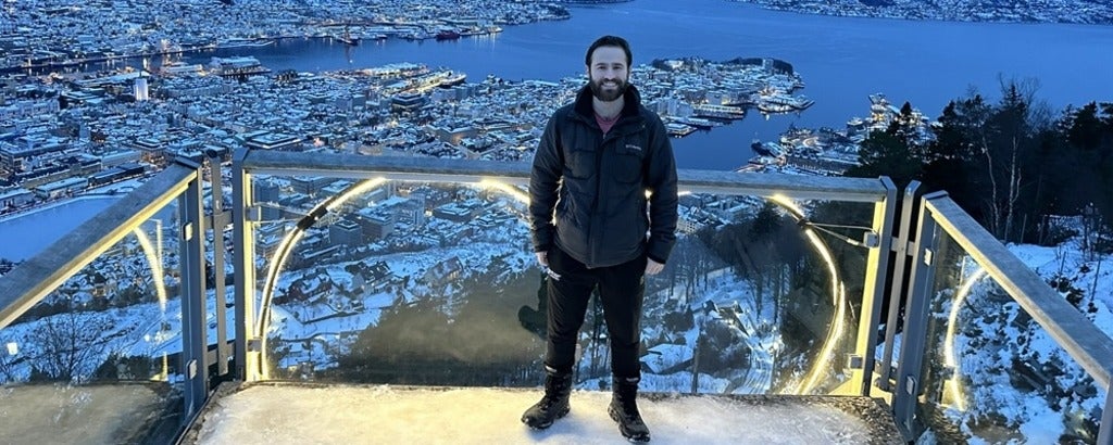 a man standing in front of water and a city below