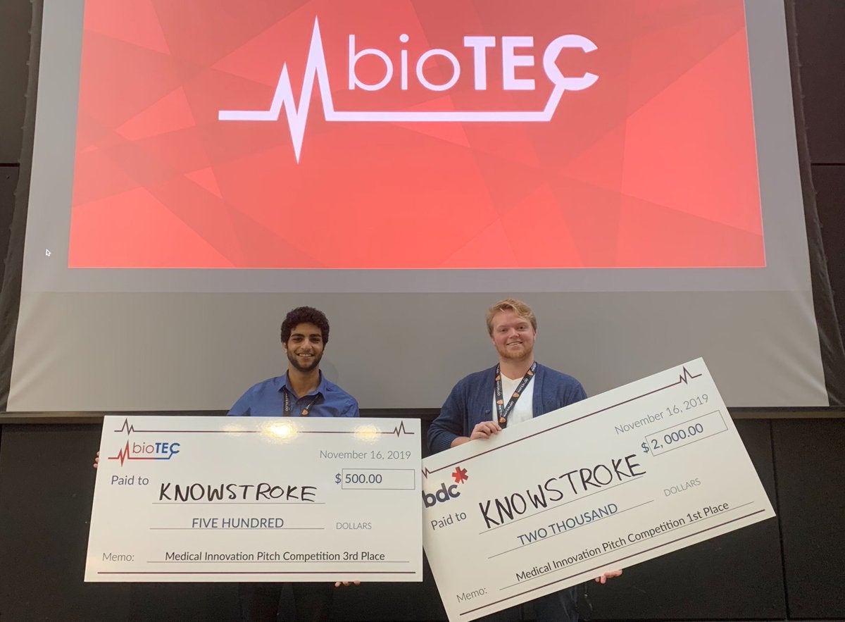 Ahmad Lakhani and Matthew Pley hold two giant cheques that represent KnowStroke’s First Place and People Choice wins at the Capstone Pitch Competition.
