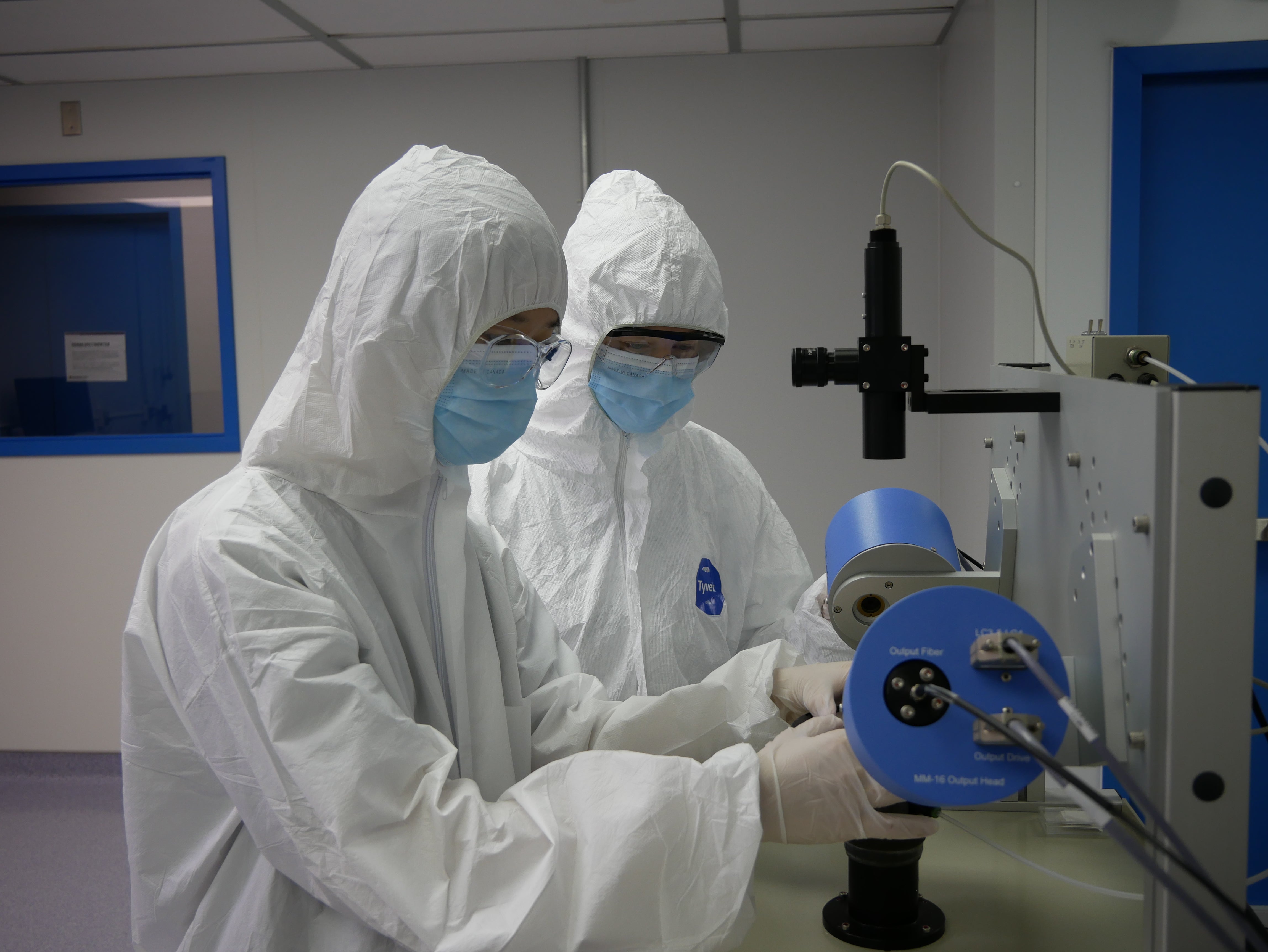 Technicians in cleanroom suits working on equipment