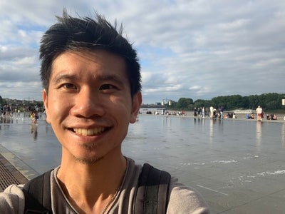 a man with black hair smiling at a beach