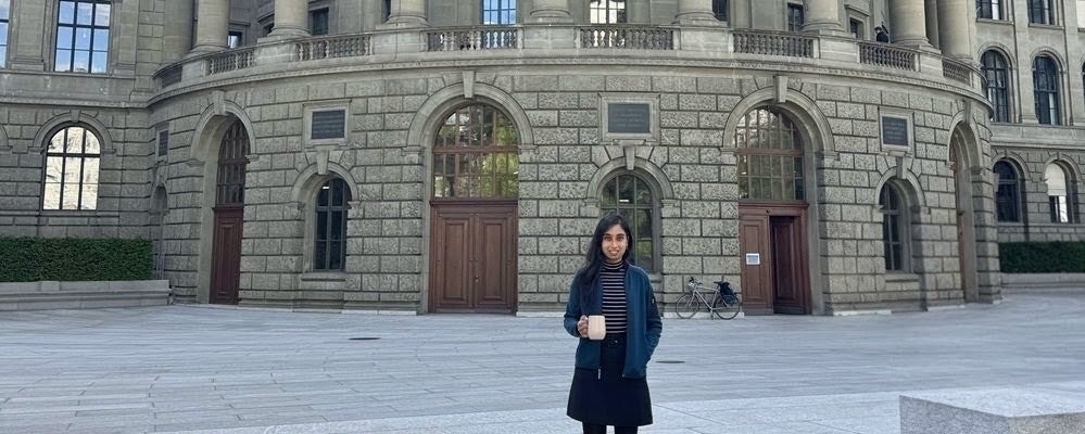 a woman with black hair holding a coffee cup in front of a brick building