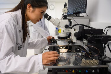 a woman looking into a microscope