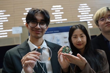 two students holding a clear and green circular object