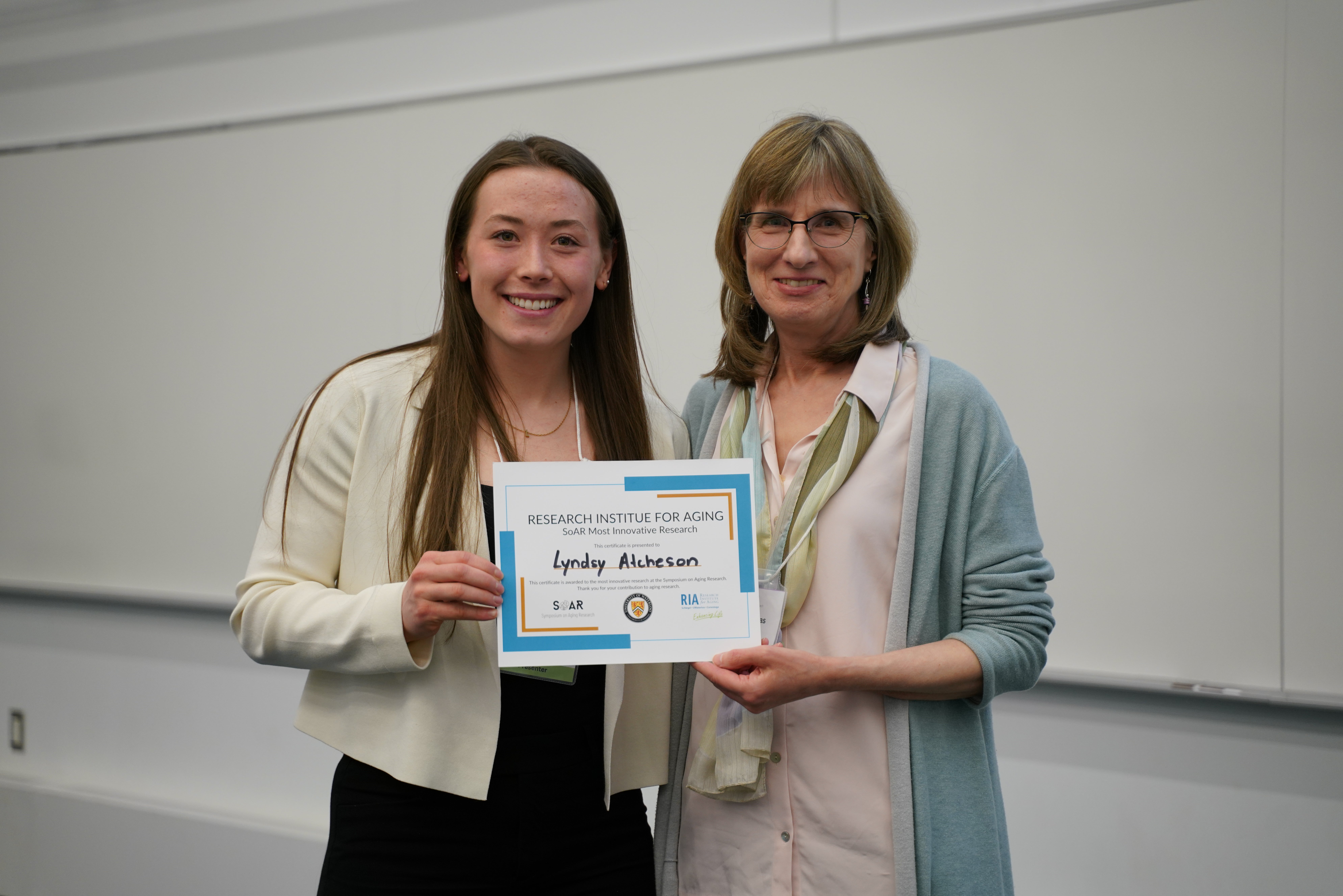 A presenter receives an award at the 2026 Symposium on Aging Research