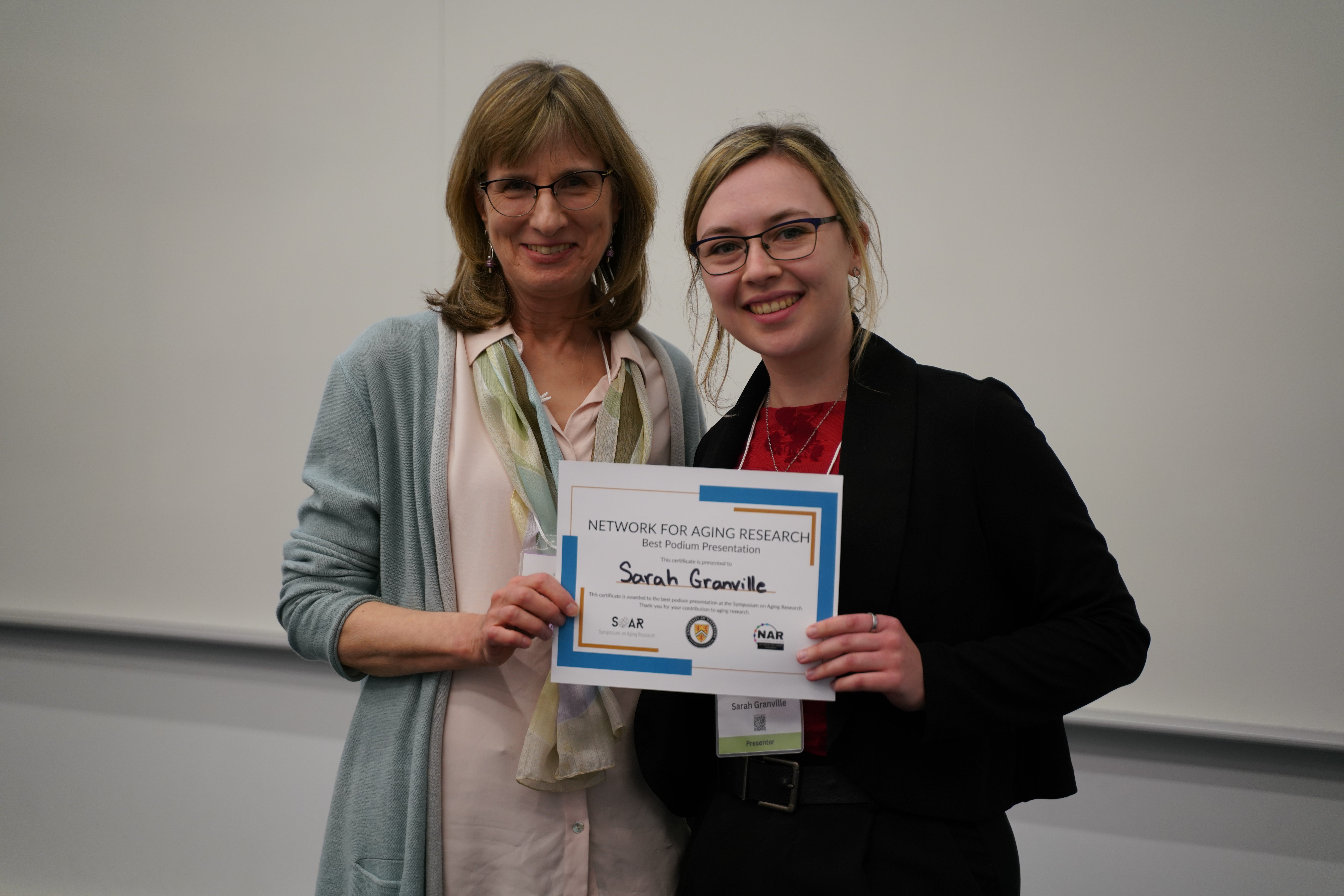 A presenter receives an award at the 2026 Symposium on Aging Research