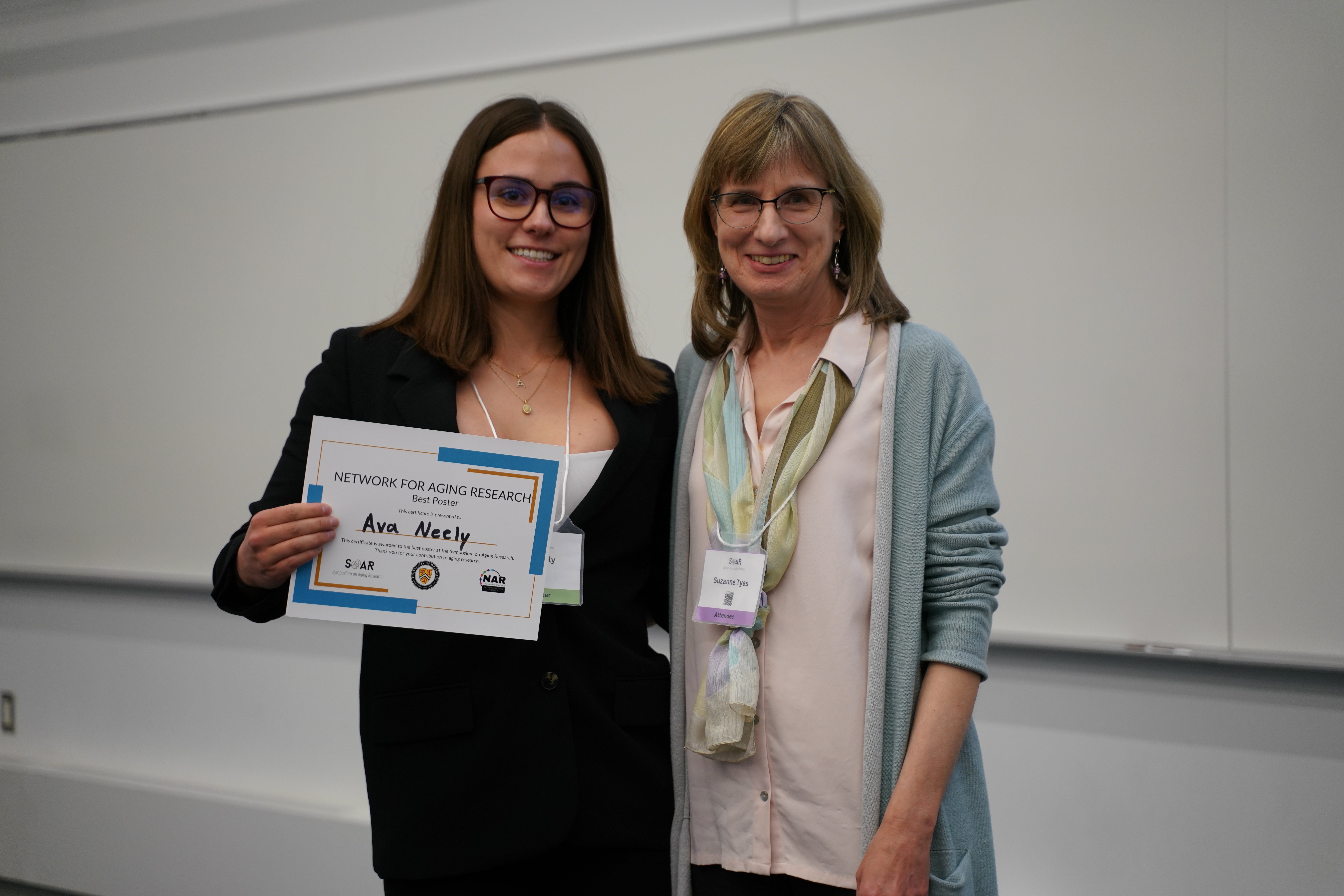 A presenter receives an award at the 2026 Symposium on Aging Research