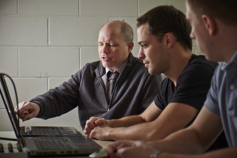 Bill McIlroy converses with lab members at a meeting.