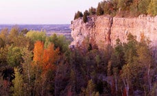 A lookout point shows autumnal trees and a sheer cliff.