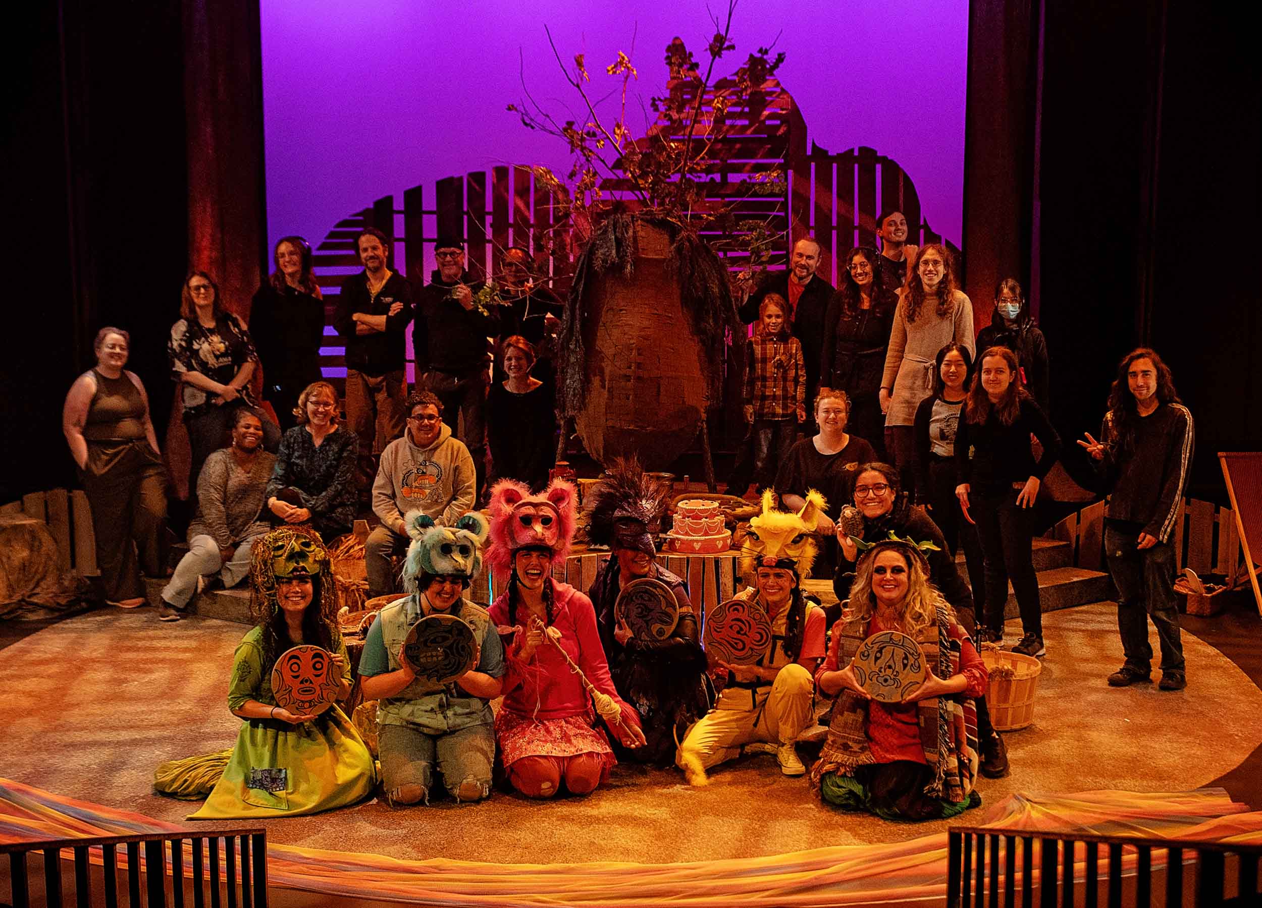 The full cast and crew of Th'owxiya gathered on stage around the feast dish