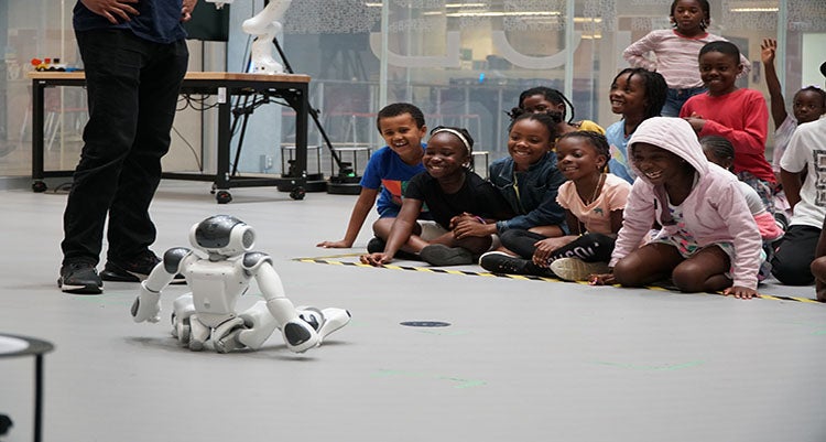 Children on Waterloo campus gleefully observing a mini robot