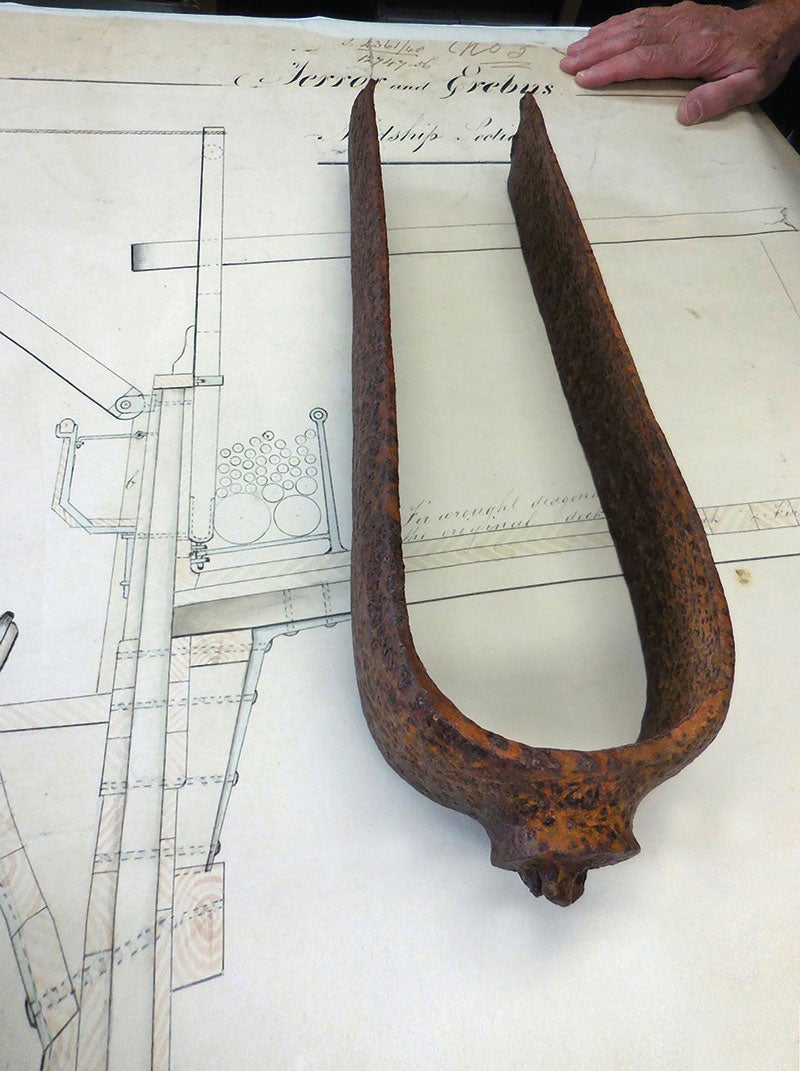 A metal piece of a ship shaped in an elonged "u", the metal is rusted and pitted