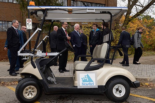 Dignitaries standing around a self-driving golf cart