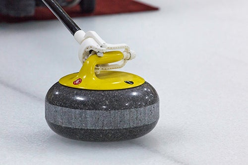 Curling device holding rock by the handle.