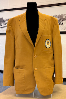 Front view of a gold jacket with a logo patch on it
