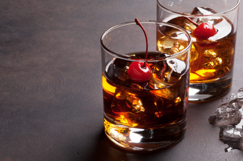 tumblers filled with whisky, each garnished with a cherry