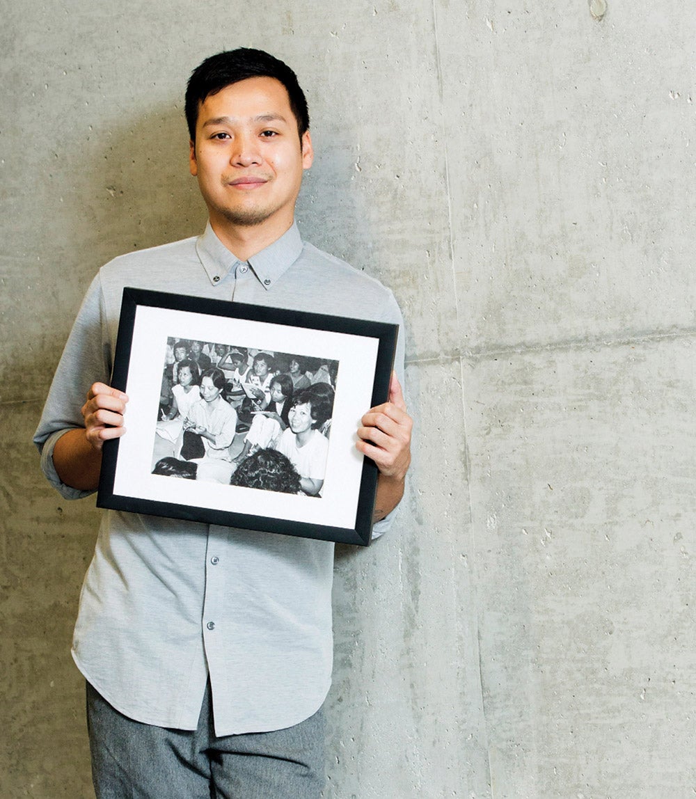 Vin Nguyen hold a framed photo showing his young mother amongst other refugee women