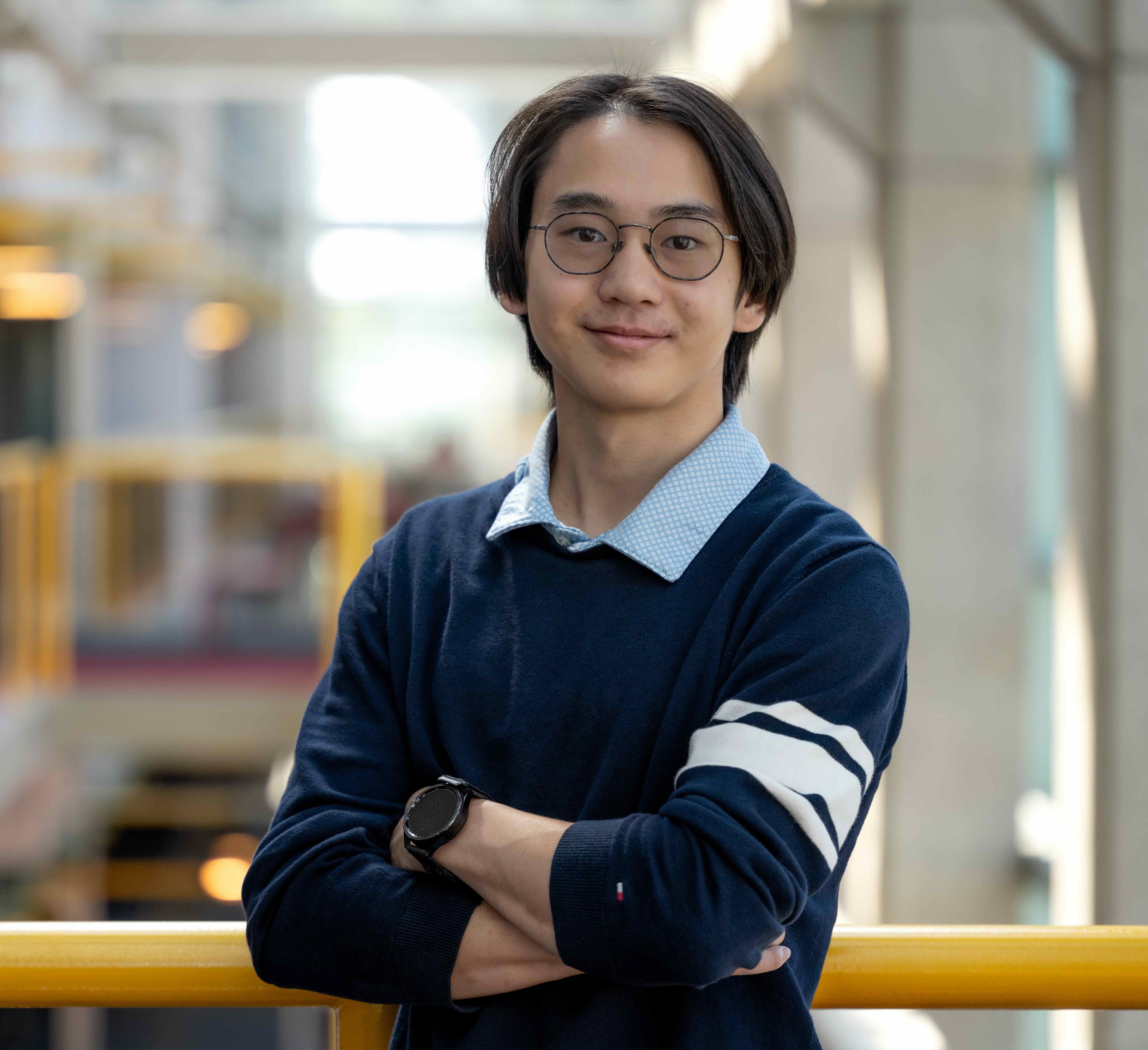 A students stands with arms crossed looking at the camera