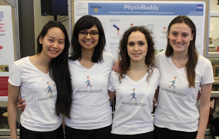 Team members of PhysioBuddy smile at the camera in front of their display.