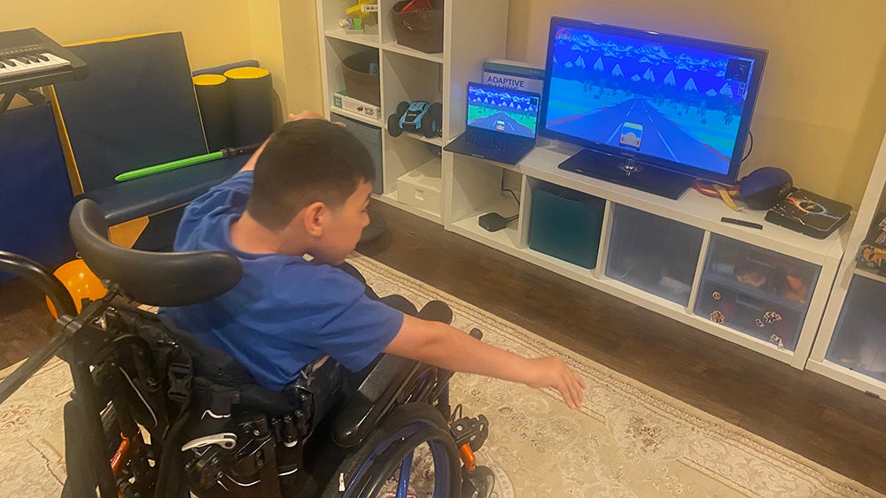 A child in a wheelchair playing a game in their living room