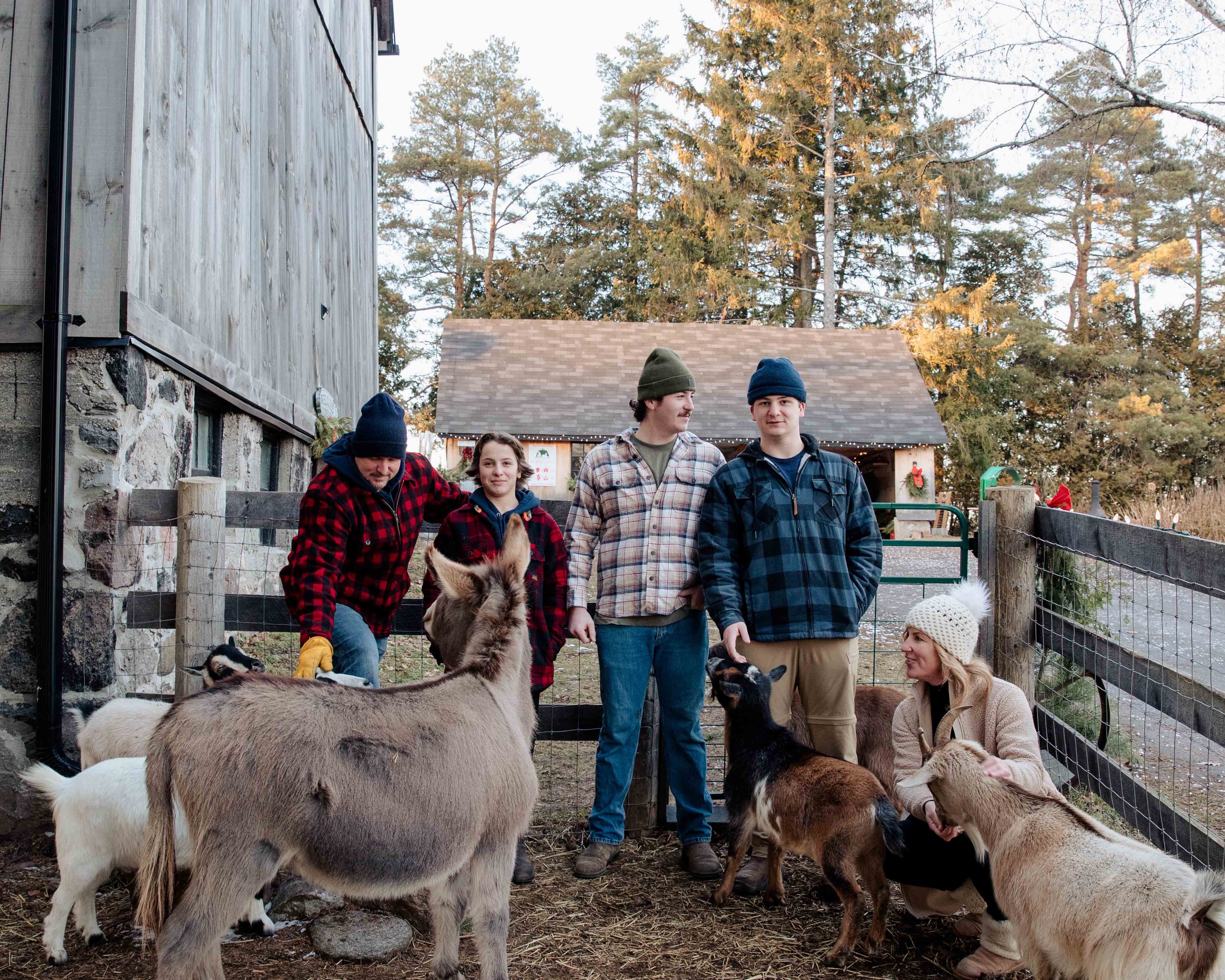 The hope family stands in a pen with a donkey and goats