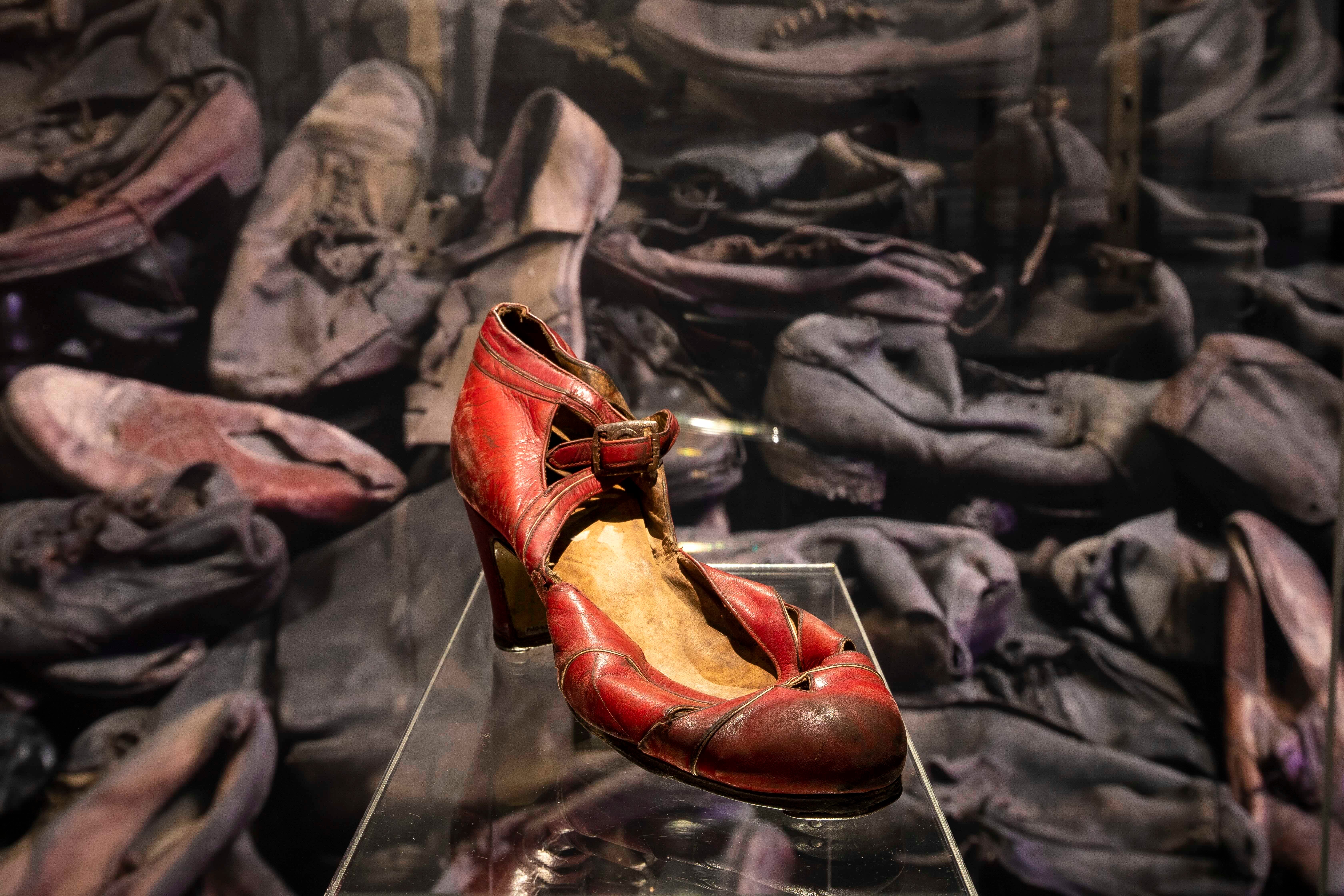 A red women's shoe in a glass case.