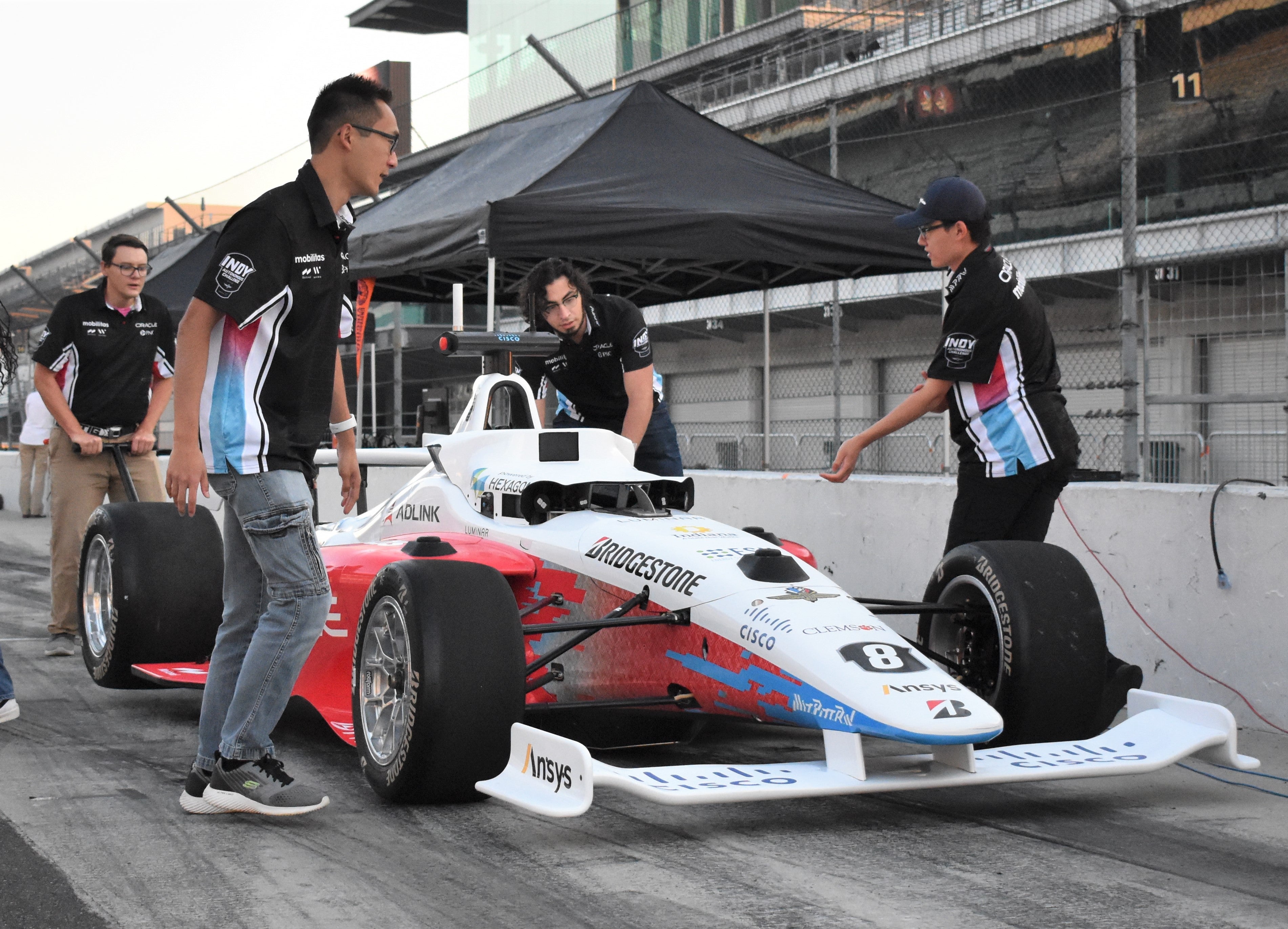 Brian Mao, front left, and Ben Zhang, front right, work on their car in the pits at the Indianapolis Motor Speedway.
