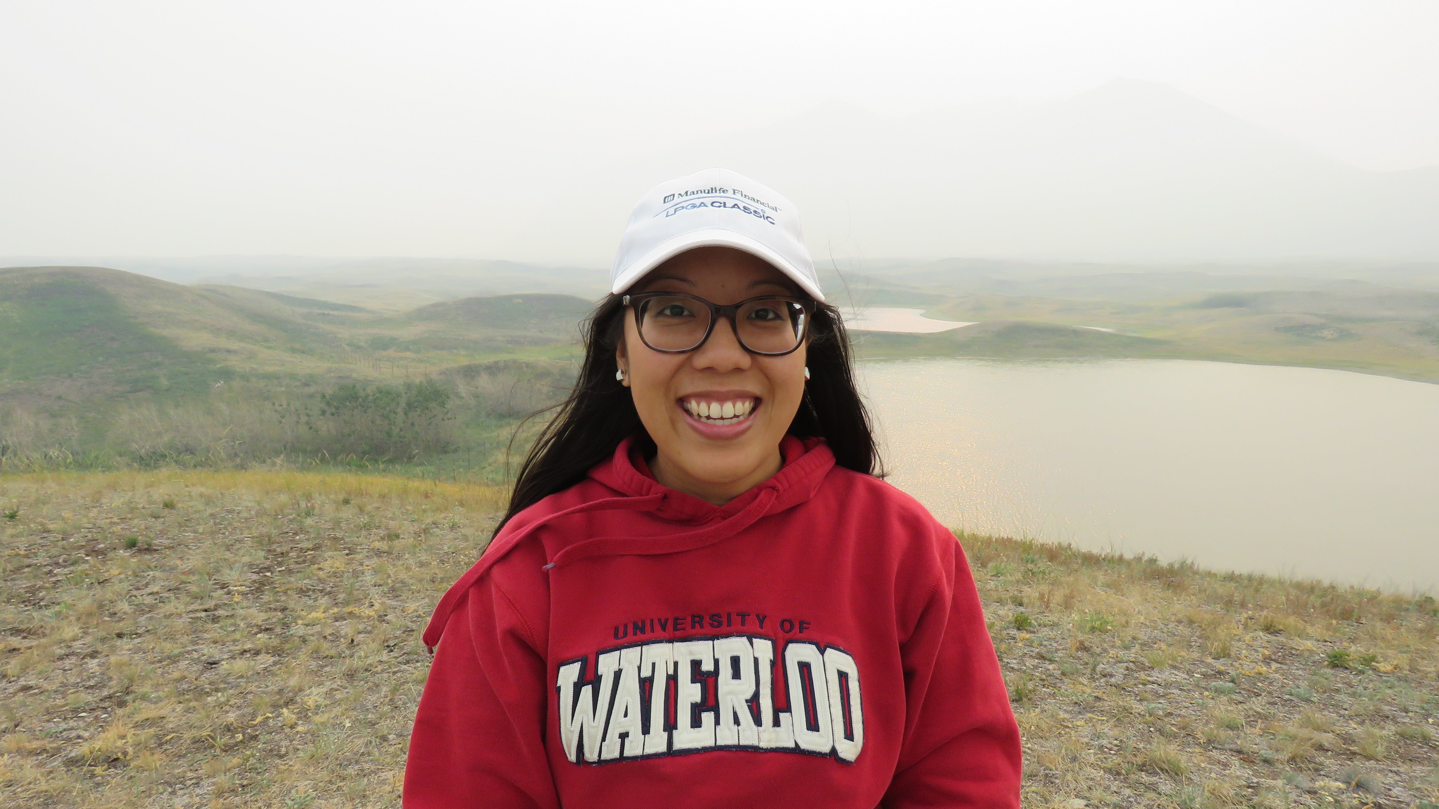 Olivia Kwok wearing UW hoodie and smiling with green hill and lake scenery in the background