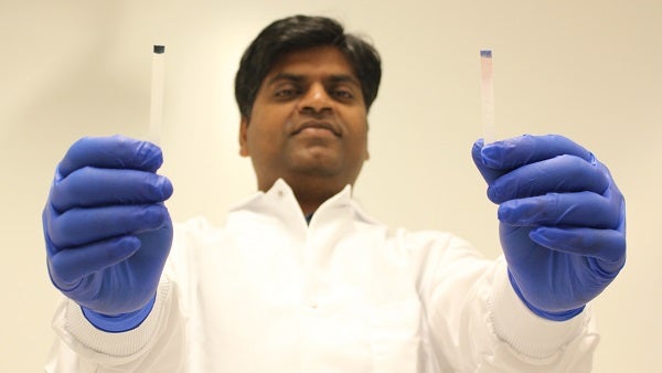 Naga Siva Kumar Gunda displays testing strip one with and without positive result for E.coli bacteria