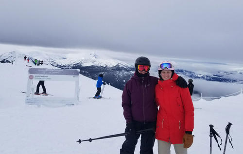 Pascale and a friend smile on top of a mountain during a skiing trip.