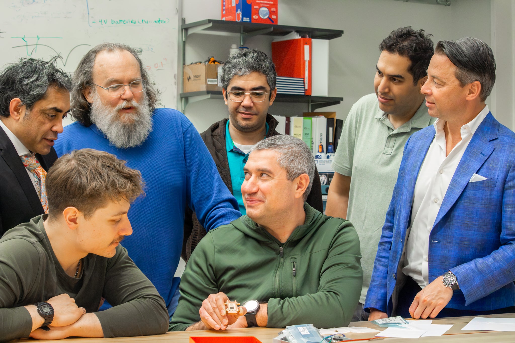 QuantumCore team huddled together talking about an amplifier for super computers