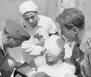 Archival photo of doctors and nurses working on a soldier in the field.