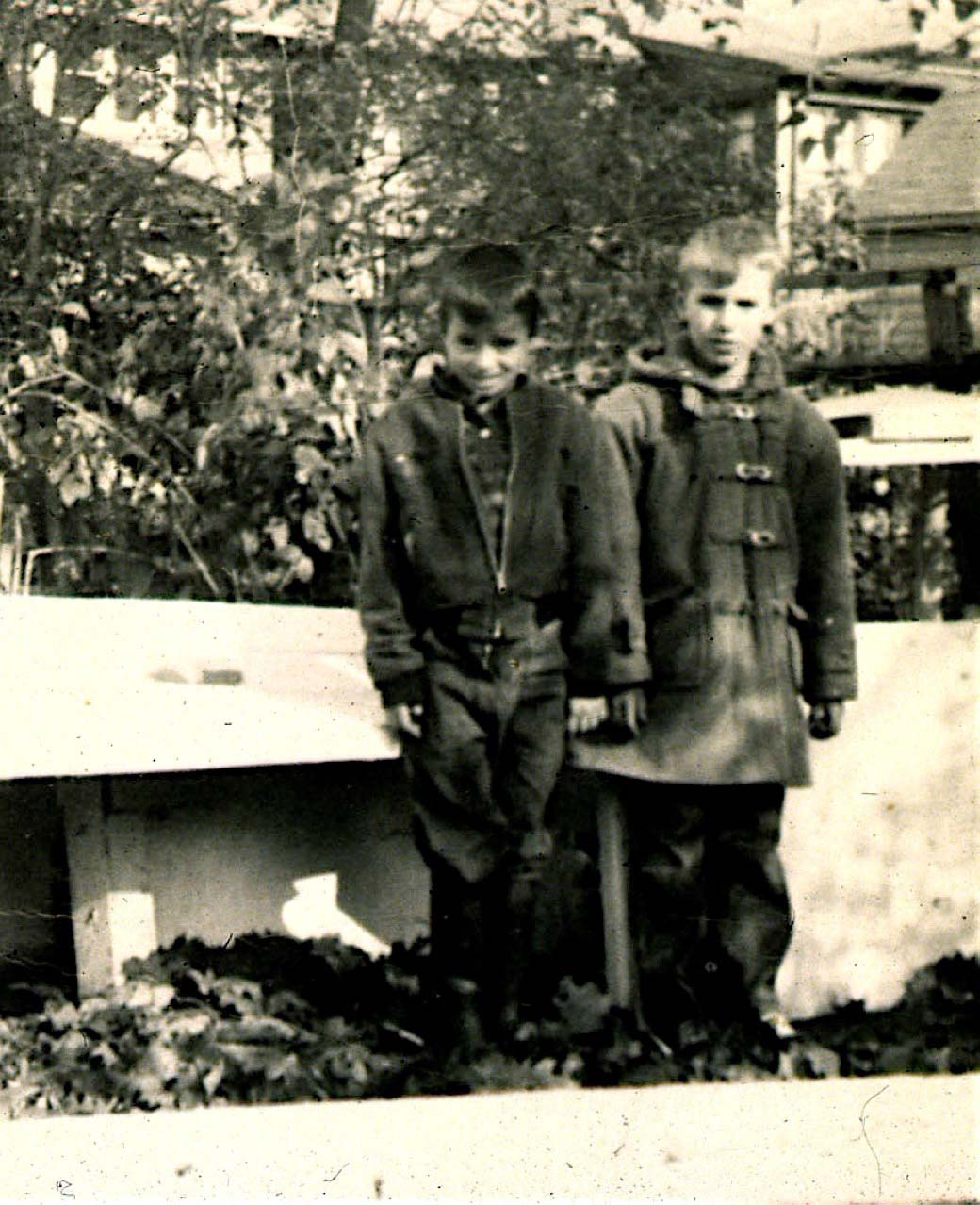 Rick and a friend pose infront of a backyard house he build as a child