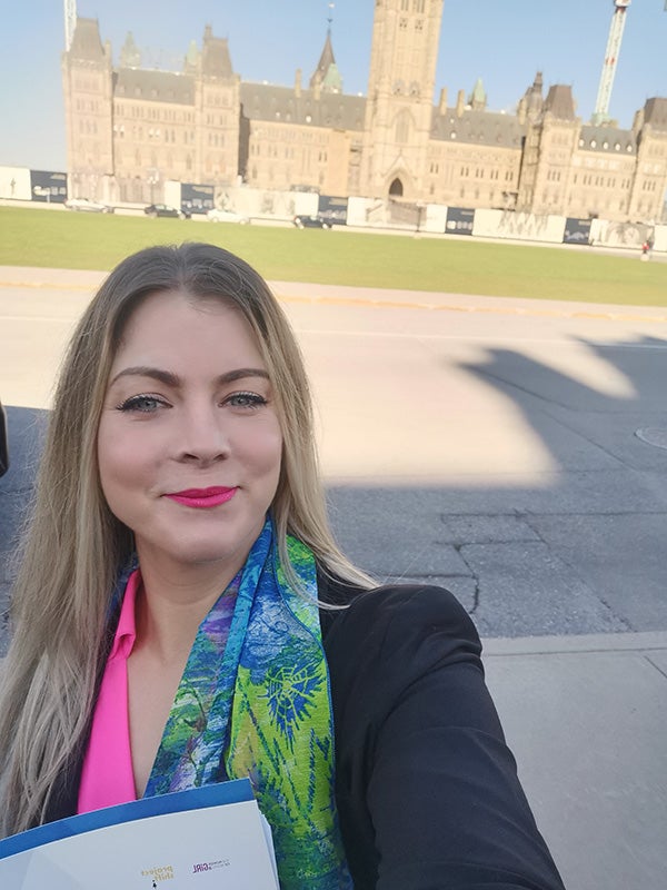 Roz Gunn standing infront of the Canadian Parliament buildings