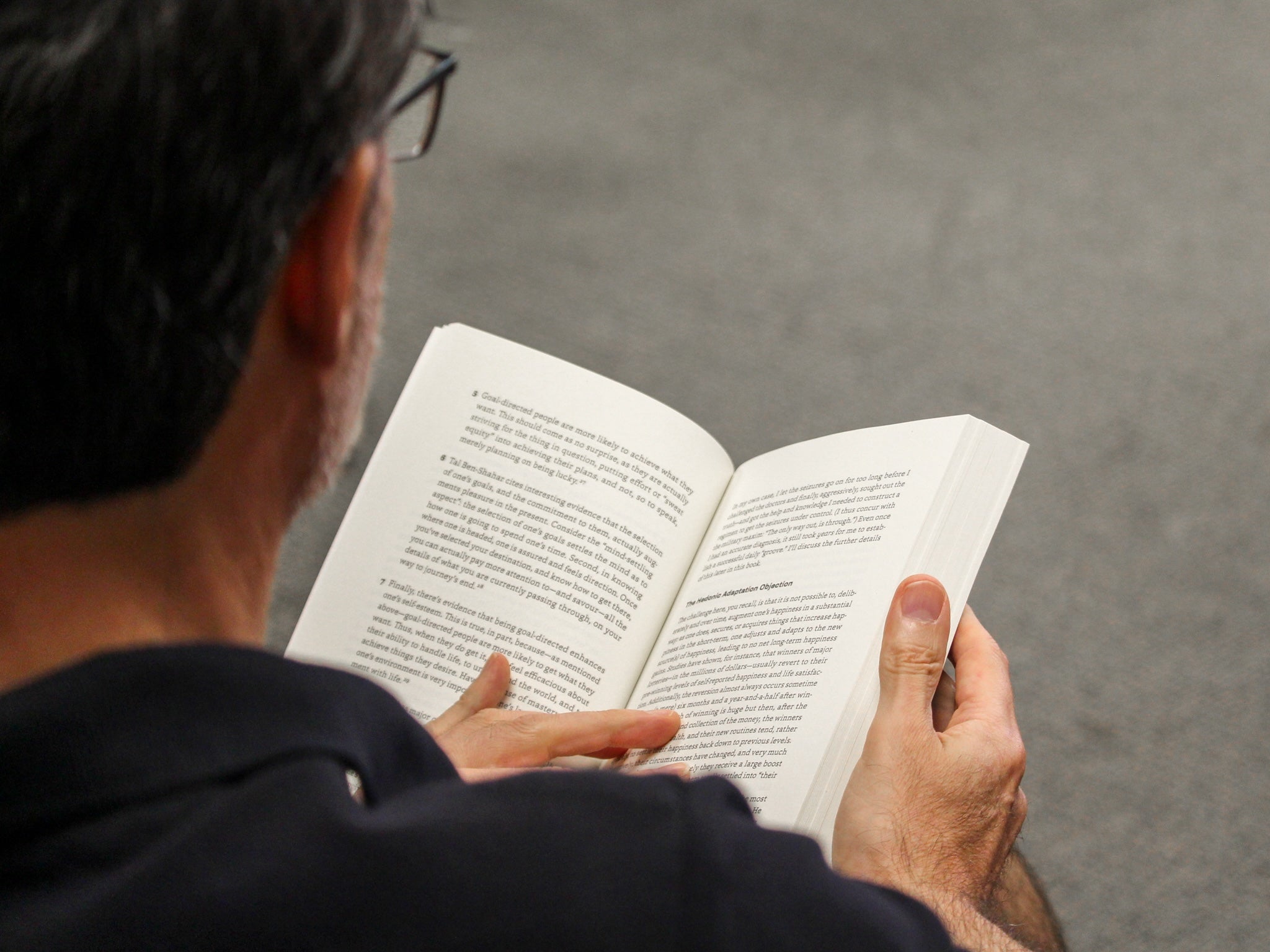 Brian Orend sits in a chair with a book open on his lap