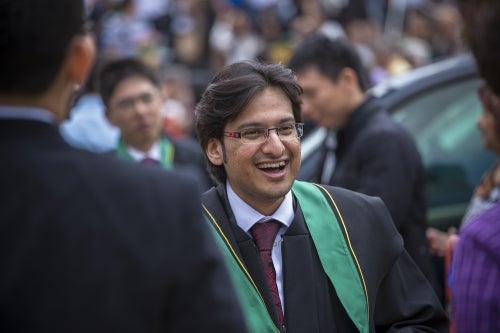 A young man greets friends at convocation