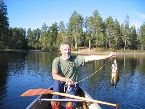 Murray holds up a fish on a canoe trip