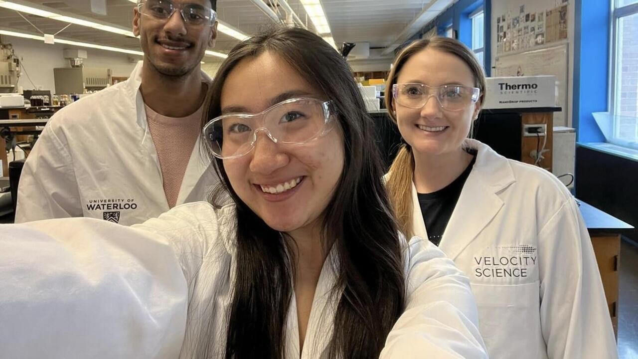 Sarah Wilson takes a selfie with two other students in goggles and lab coats