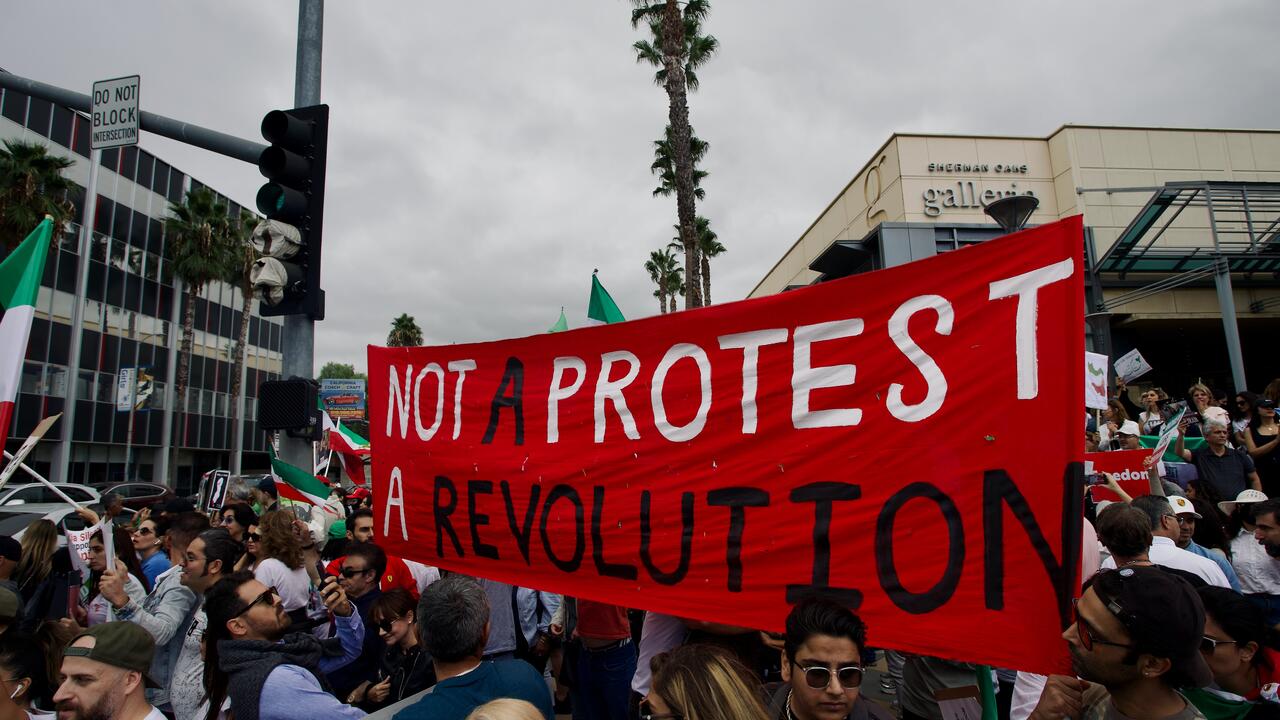 Banner in crowd of protesters that reads, &quot;Not a protest, a revolution.&quot;