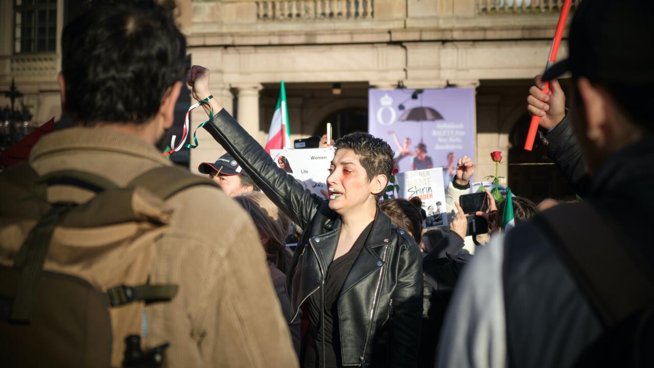 Iranian woman standing in crowd with folded fist in protest