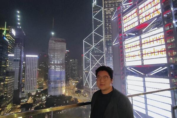 Jeremy Zhu stands in front of the Hong Kong skyline