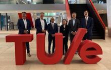 Vivek Goel and Ian Rowlands standing with their hosts at TU/e behind a TU/e sign.